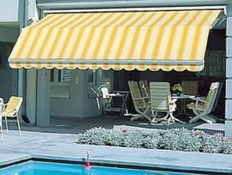 Frontansicht einer gelb-weiß gestreiften Doppel-Gelenkarm-Markise mit Knick, über Stühlen, Tisch und Pool.