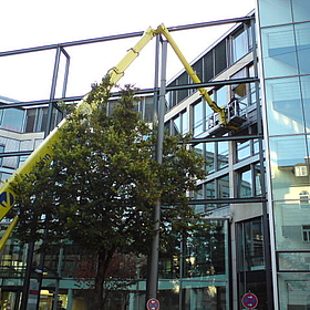 Eine Glasfassade eines Neubaus mit gelbem Montagekran davor