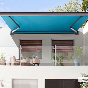 Frontansicht einer blauen, ausgefahrenen Markise Casabox von Klaiber über Balkon mit Glasgeländer und halb geöffneten Rolladen an weißer Hauswand.