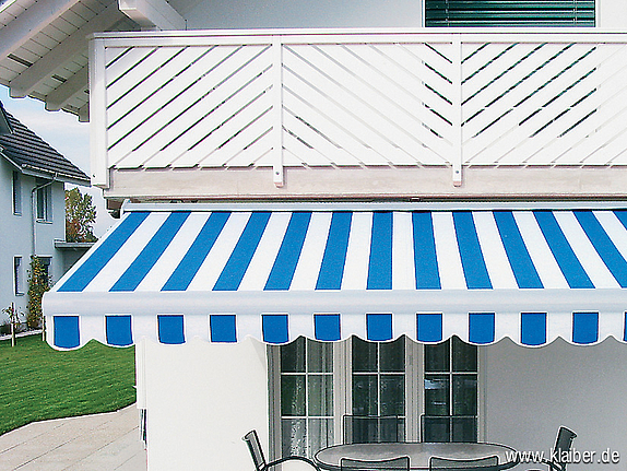 Frontansicht einer blau-weißen, ausgefahrenen Gelenkarm-markise über Terrasse mit Tisch und Stühlen an weißem Haus.